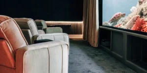Cozy home theater with plush recliners and large screen displaying underwater scene with sea turtle.