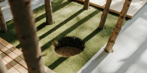 Circular hole dug in the forest ground surrounded by tree trunks and wooden decking