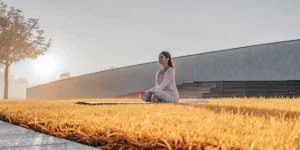 Woman meditating in the garden at sunrise on a yoga mat